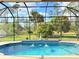Relaxing screened-in pool with fountains, surrounded by tropical greenery and blue skies at 2329 Como St, Port Charlotte, FL 33948