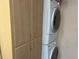 A laundry area featuring a stacked washer and dryer, accompanied by convenient storage cabinets at 24862 Us Highway 19 N # 3001, Clearwater, FL 33763