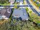 Drone photo of the home with a screened-in pool, large roof, mature landscaping, and paved street at 2903 Marble Crest Dr, Land O Lakes, FL 34638