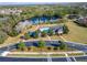 Aerial shot of neighborhood clubhouse overlooking lake with pool, shade structures, and parking at 2903 Marble Crest Dr, Land O Lakes, FL 34638