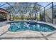 A screened-in pool and spa with outdoor seating, with a view of blue skies, blue water and mature trees at 2903 Marble Crest Dr, Land O Lakes, FL 34638