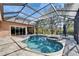 A screened-in pool and spa with outdoor seating, with a view of blue skies, blue water and mature trees at 2903 Marble Crest Dr, Land O Lakes, FL 34638