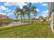 Beautiful backyard featuring lush green grass, black metal fence, pond, and mature palm trees at 3339 Brenford Pl, Land O Lakes, FL 34638