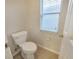 Cozy half-bath featuring a toilet, a window with privacy blinds, and beige tile floor at 3339 Brenford Pl, Land O Lakes, FL 34638