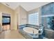 Tiled bathroom with an oval soaking tub, glass block window, and separate shower at 3339 Brenford Pl, Land O Lakes, FL 34638