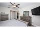 This bedroom features neutral walls, carpet, ceiling fan and dresser with television at 5316 Stoic Vale Dr, Wimauma, FL 33598