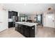 Open-concept kitchen with dark cabinets, stainless appliances, island, and seamless connection to the living and dining areas at 5316 Stoic Vale Dr, Wimauma, FL 33598