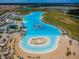 Overhead view of the community lagoon highlighting the inflatable obstacle course, beach, and lounge area at 5316 Stoic Vale Dr, Wimauma, FL 33598