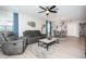 Cozy living room with a ceiling fan, a plush gray sofa, and a neutral rug over light wood floors at 5316 Stoic Vale Dr, Wimauma, FL 33598