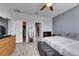 Bedroom boasts a ceiling fan, gray plank flooring and views into the bathroom and walk-in closet at 10019 Celtic Ash Dr, Ruskin, FL 33573