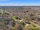 An aerial view displays homes with pools and tree lined streets with a wooded backdrop at 10171 Patrick St, Brooksville, FL 34601