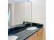 Bathroom with double sinks, dark granite countertop, and a large mirror at 10346 Carrollwood Ln # 171, Tampa, FL 33618