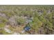 Aerial view of a home nestled among tall trees with a long driveway and fenced-in backyard at 17480 Nuthatch Rd, Weeki Wachee, FL 34614