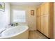 Bathroom with a jetted tub, storage cabinets and a decorative glass block window at 17480 Nuthatch Rd, Weeki Wachee, FL 34614