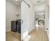 Hallway featuring wood floors, a sliding barn door leading to the laundry area, and a view into the open-concept kitchen at 17628 Breakaway St, Land O Lakes, FL 34638