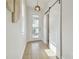 Bright hallway featuring wood floors, natural light, a decorative sliding barn door, and modern light fixtures at 17628 Breakaway St, Land O Lakes, FL 34638