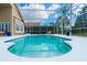 Enclosed pool with beautiful blue water, surrounded by a white deck and tropical landscaping at 18934 Avenue Biarritz, Lutz, FL 33558