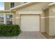 Attached one-car garage door of a tan townhouse with a manicured green hedge at 2032 Sunset Meadow Dr, Clearwater, FL 33763