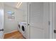 Laundry room with washer and dryer, white walls, wood floors, and a bright window at 2032 Sunset Meadow Dr, Clearwater, FL 33763