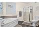 Bathroom showcasing a soaking tub, glass enclosed shower, toilet, and tile floors at 2717 Via Cipriani # 620A, Clearwater, FL 33764