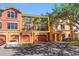 View of an orange, three-story townhouse with garage and a white car parked out front at 2717 Via Cipriani # 623B, Clearwater, FL 33764