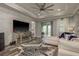 Spacious living room with tray ceiling, fan, brick accent wall, hardwood flooring, and sliding doors at 3042 Marine Grass Dr, Wimauma, FL 33598