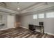 Bright home office featuring three windows, wood floors, and sleek black and chrome furniture at 3042 Marine Grass Dr, Wimauma, FL 33598