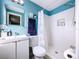 Bathroom featuring tiled shower, single sink vanity, toilet and bright blue walls at 3142 Domino Dr, Holiday, FL 34691