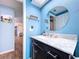 Bathroom with a blue wall, vanity with granite countertop and a round mirror at 3142 Domino Dr, Holiday, FL 34691