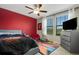 Bright bedroom featuring a vibrant red accent wall, ceiling fan, and a basketball-themed rug at 3568 Pine Ribbon Dr, Land O Lakes, FL 34638