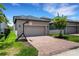 Home featuring a two-car garage, brick paver driveway, basketball hoop and manicured lawn at 3568 Pine Ribbon Dr, Land O Lakes, FL 34638