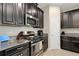 Well-equipped kitchen featuring dark cabinetry, granite countertops, and modern stainless steel appliances at 3568 Pine Ribbon Dr, Land O Lakes, FL 34638