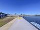 Waterfront property featuring a dock with yellow lounge chairs, lawn and beautiful lake view on a clear sunny day at 4941 Waterside Dr, Port Richey, FL 34668