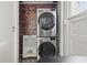 Laundry area featuring stacked washer and dryer with exposed brick at 5807 N Branch Ave, Tampa, FL 33604