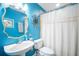 Vibrant bathroom with a white sink, toilet, and shower featuring bright blue walls and decorative accents at 6411 Grenada Island Ave, Apollo Beach, FL 33572