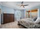 Primary bedroom features blue walls, patterned carpet, ceiling fan, access to balcony and a wooden dresser at 6411 Grenada Island Ave, Apollo Beach, FL 33572