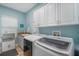 Laundry room features white cabinets, a utility sink, and a newer front loading washer and dryer at 6411 Grenada Island Ave, Apollo Beach, FL 33572