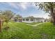 Expansive backyard featuring a manicured lawn, screened-in porch, and lush, mature landscaping at 6655 Colony S Dr, St Petersburg, FL 33705