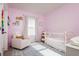 Charming Bedroom with pink walls, a white crib, and a comfortable armchair and patterned rug at 9258 Rock Harbour Way, Tampa, FL 33637