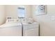 Functional laundry room showcasing a white washer and dryer setup with natural light from a window at 10582 Dusty Boot Rd, Land O Lakes, FL 34638