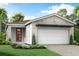 Modern home exterior with attached two-car garage, simple landscaping, and neutral colors at 12233 New Tranquility Path, Venice, FL 34293