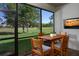 Screened-in lanai with a wooden table set that overlooks a lush green golf course at 12233 New Tranquility Path, Venice, FL 34293