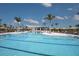 Scenic view of a community pool featuring sun loungers, umbrellas and tropical landscaping at 12233 New Tranquility Path, Venice, FL 34293