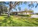 Charming home featuring mature trees, lush lawn, and a screened-in porch with manicured shrubbery at 1227 Queen Anne Dr # C, Palm Harbor, FL 34684