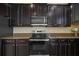 Close-up of a modern oven and countertop with dark cabinets and stainless steel microwave above at 19429 Paddock View Dr, Tampa, FL 33647