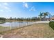 Backyard featuring a white picket fence and a tranquil water view, complemented by a lush lawn and clear skies at 2619 Ravendale Ln, Holiday, FL 34691