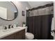 Classic bathroom features a dark wood vanity with white basin sink, round mirror, and black shower curtain at 2619 Ravendale Ln, Holiday, FL 34691