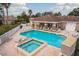 Relaxing community pool with lounge chairs, tiled pool deck, fencing, palm trees, and a nearby hot tub for residents at 2619 Ravendale Ln, Holiday, FL 34691