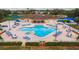 Aerial view of a community pool area featuring a unique heart-shaped pool, sun loungers, and blue sunshades at 2619 Ravendale Ln, Holiday, FL 34691