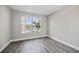 Bedroom with wood-look floors, light gray walls, and a window with a view of the neighborhood at 2914 Westmoreland Ct, New Port Richey, FL 34655